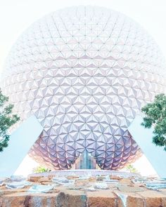 the spaceship dome at disney world is shown in front of some trees and water fountains