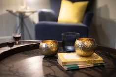 two gold cups sitting on top of a wooden table next to a blue chair and yellow pillows