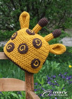 a crocheted giraffe hat sitting on top of a wooden bench