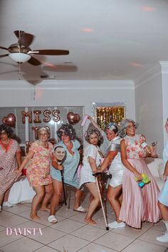 a group of women standing next to each other in front of a ceiling fan