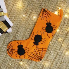 an orange stocking with black spider webs on it next to a gold ribbon