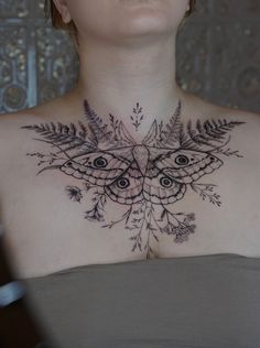 a woman with a butterfly and leaves tattoo on her chest is looking up at the camera