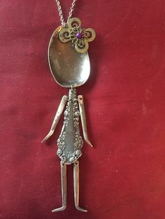 a silver plate with a spoon in the shape of a woman's face on a red background