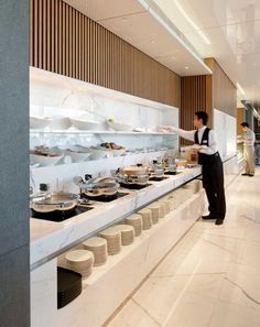 a woman standing in front of a counter filled with plates and pans on it