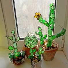 three potted plants sitting next to each other on a window sill