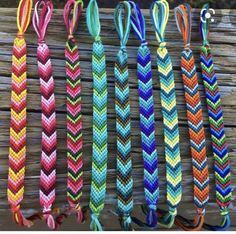 several colorful braided bracelets hanging on a wooden fence