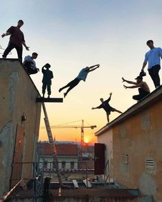 people are doing tricks on the roof of an old building at sunset or sunrise time