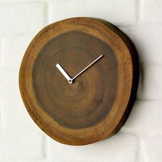 a wooden clock on a white brick wall