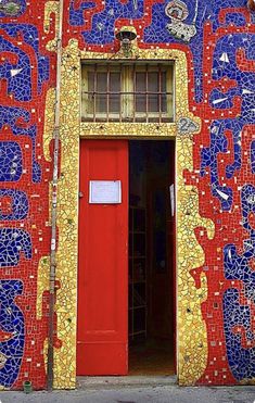 a red door is in the middle of a colorful building with many designs on it