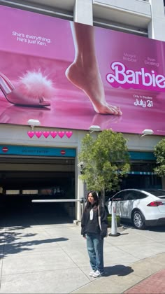 a woman standing in front of a pink advertisement