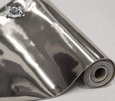 a roll of shiny metallic paper on top of a white table with a silver seal