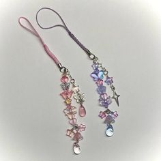 two long necklaces with charms hanging from it's sides on a white surface