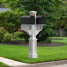 a white mailbox sitting on the side of a road next to a lush green field