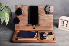 a wooden desk with an alarm clock, cell phone and other personal items on it