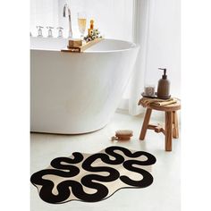 a bath room with a tub and a rug on the floor in front of it