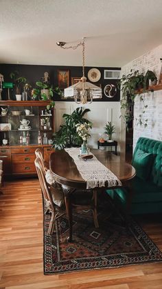 a dining room table with green chairs and plants on the wall behind it, along with potted plants