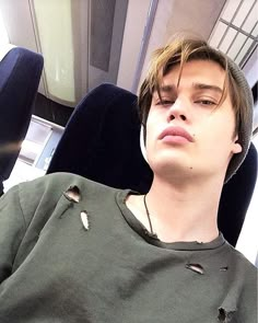 a young man sitting in an office chair with his head resting on the arm rest