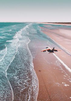 an airplane is flying low over the water at the beach with waves crashing on it