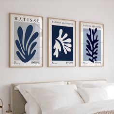 three blue and white art prints hanging on the wall above a bed in a bedroom