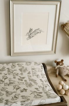 a bed with an animal print on it next to a framed drawing and stuffed animals