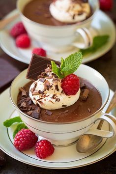 two cups filled with chocolate pudding and topped with raspberries