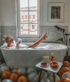 a woman laying in a bathtub surrounded by balloons