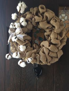 a wreath made out of burlock and cotton on a wooden door with an iron hook