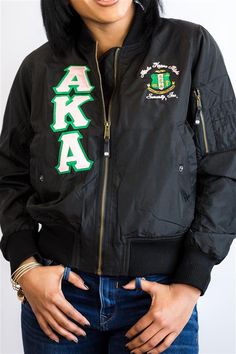 a woman wearing a black jacket with the letters aka on it and green lettering