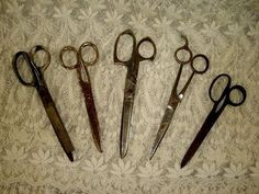 five pairs of scissors sitting on top of a white tablecloth covered floor next to each other