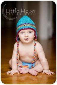 a baby wearing a knitted hat sitting on the floor