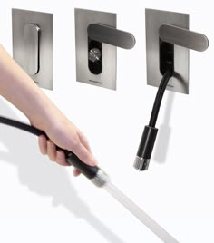 a person is holding a black cord and plugged in to a wall mounted faucet