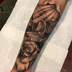 a black and white tattoo on the arm of a person with a rose in it