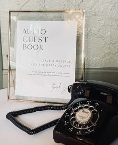 an old - fashioned telephone sits on a table next to a sign that reads audio guest book