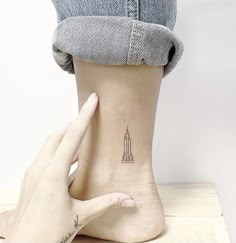 a woman's foot with a small tattoo on it and a rocket ship in the background