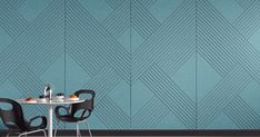 two chairs sitting at a table in front of a wall with geometric designs on it