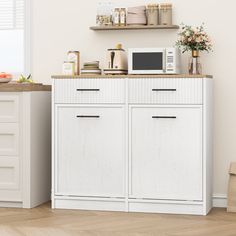 a kitchen with white cabinets and wooden floors in front of a window, microwave on top of the cabinet