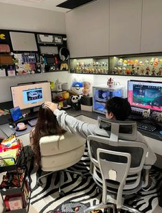 a person sitting at a desk in front of two computer monitors