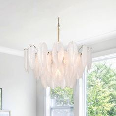 a chandelier hanging from the ceiling in a room with white walls and windows