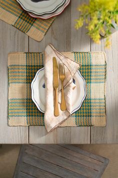 a place setting on a wooden table with plates and utensils in front of it