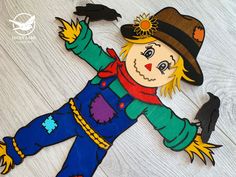 a paper cut out of a scarecrow wearing a hat and holding a black bird