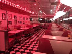 an empty diner with checkered floor and red lighting on the ceiling, along with black and white walls