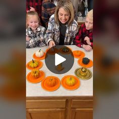 a woman and children are around a table with pumpkins