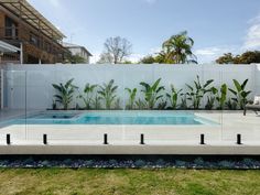 an empty swimming pool in the middle of a yard with grass and plants around it