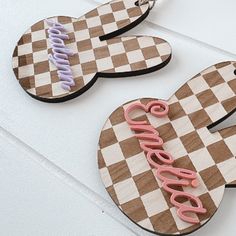 two wooden heart shaped key chains with the word love spelled in pink and purple on them