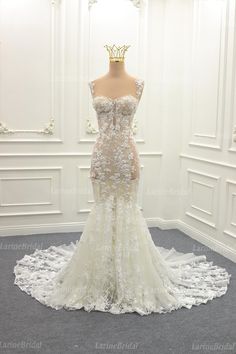 a wedding dress on display in front of a white wall with ornate carvings and flowers