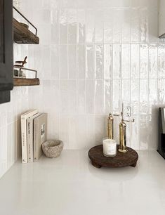 a kitchen with white tile and wood accents on the countertop, along with bookshelves