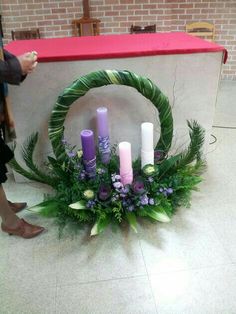 a wreath with candles and greenery on the floor