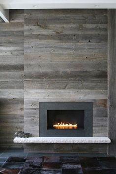 a fireplace in a living room with wood paneling on the wall and tile floor