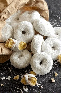 powdered doughnuts are sitting in a brown paper bag on a black surface