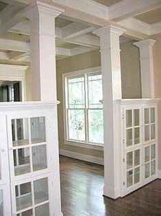 an empty living room with wood floors and white columns